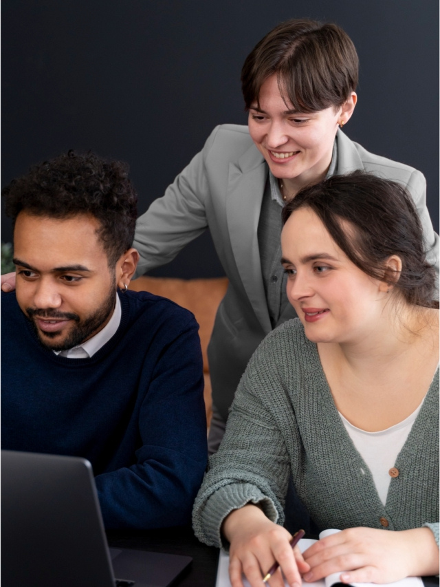 Three coworkers collaborating around a laptop.